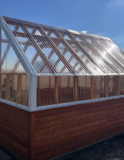 Outdoor, beautiful greenhouse structure with glass and cherry wood.