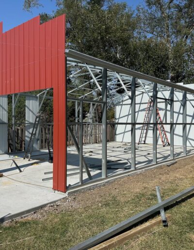 The front and back structure of an enormous metal shed being put up on concrete pad.