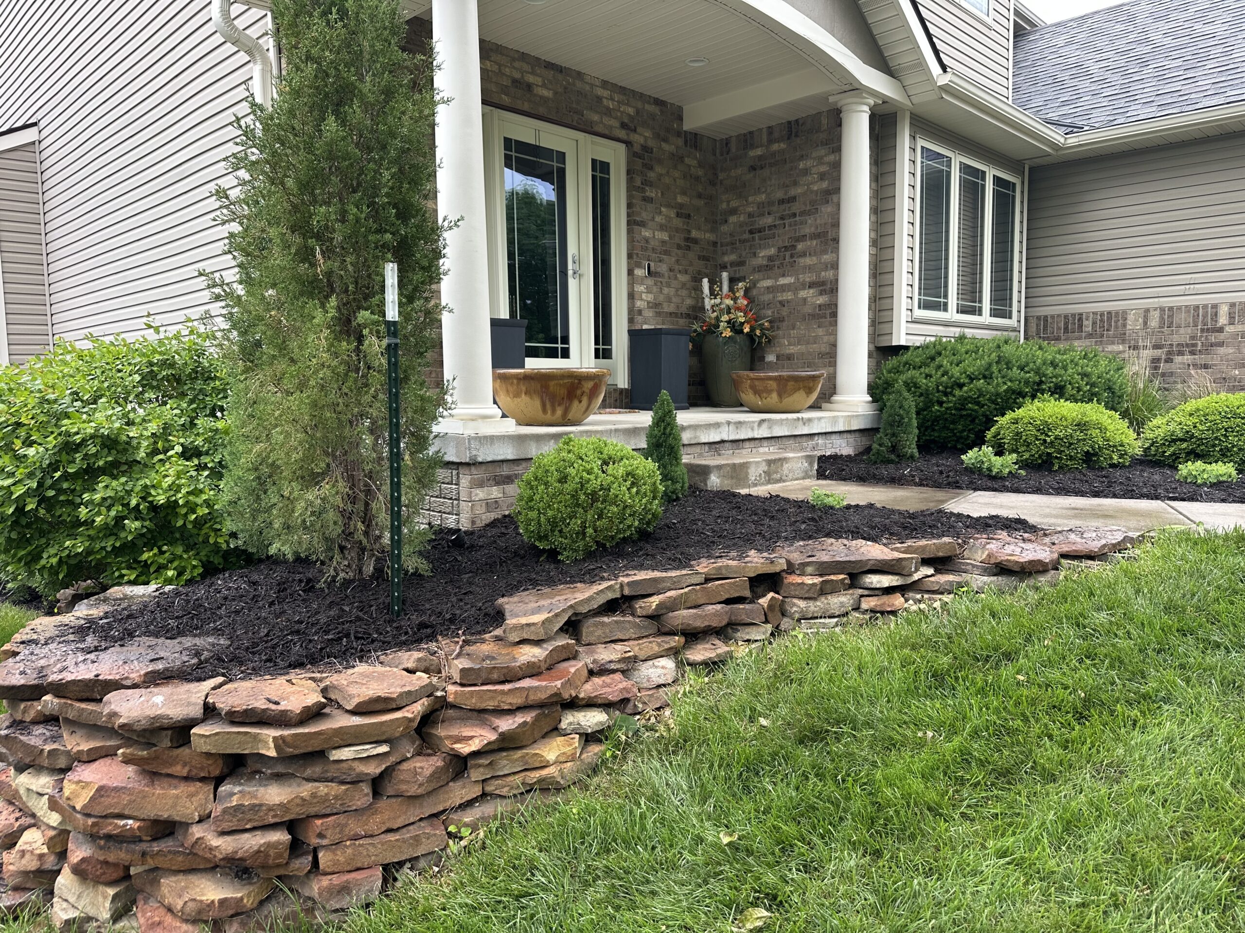 A beautiful new mulch beds created in a wavy shape on the side of a home with a beautiful new deck.